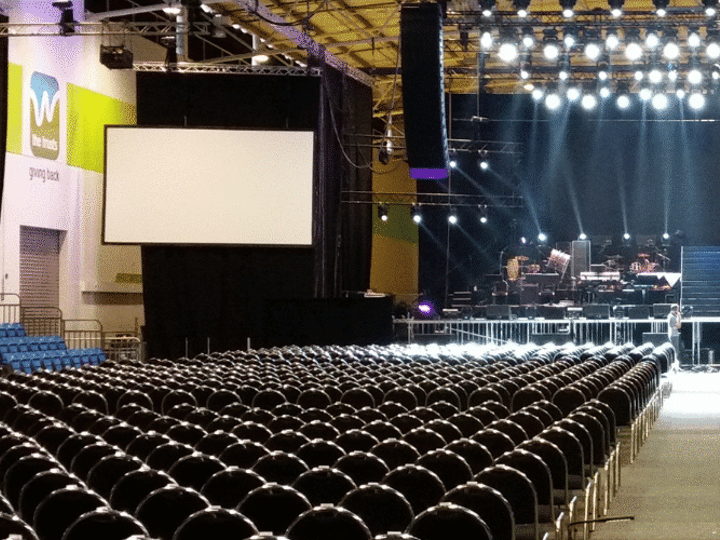 Large indoor arena floor set with rows of chairs facing a lit stage