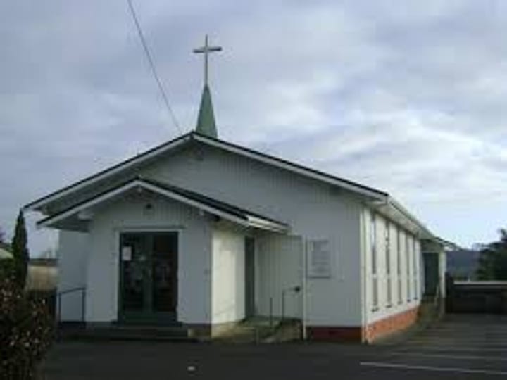 Plain white church building with cross on roof