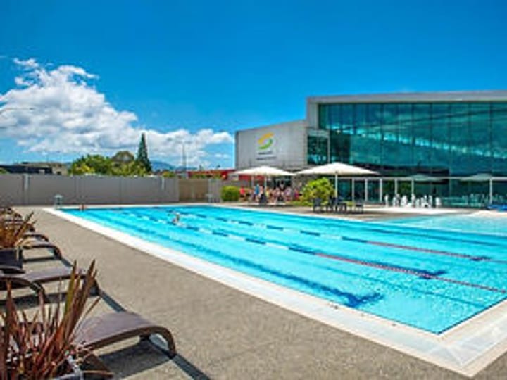 Outdoor swimming pool with lane markings and glass-fronted building behind