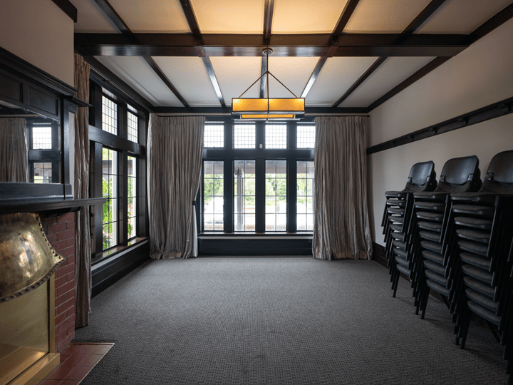 Room with dark timber beams, pendant light, fireplace and large windows