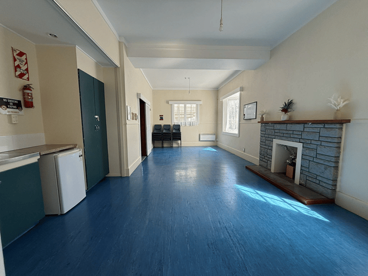 Open hall interior with blue painted floor and fireplace at one end