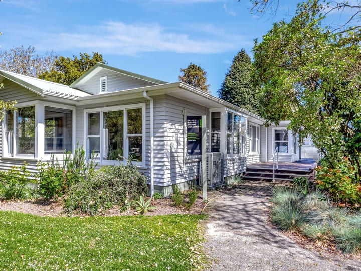 Single-storey weatherboard building with garden surrounds and entry steps