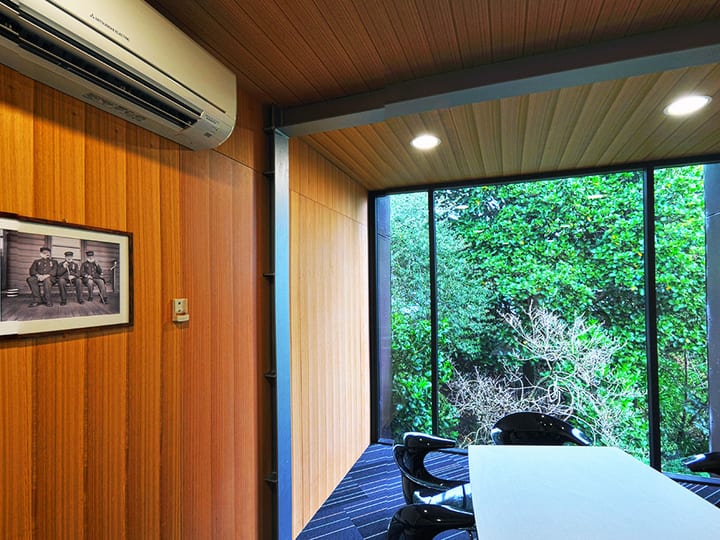 Boardroom with oval timber table, red chairs and full-height garden windows