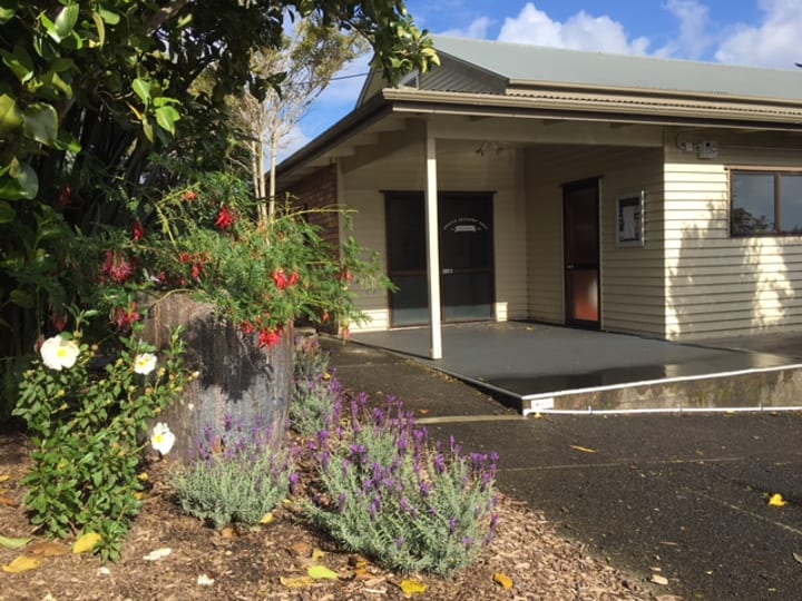 Cream weatherboard hall with covered entry porch, mixed garden planting in foreground