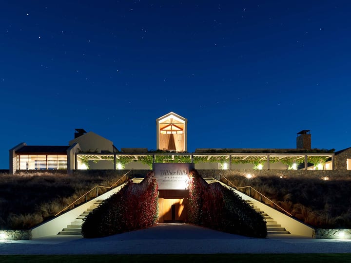 Illuminated winery buildings at dusk with landscaped grounds
