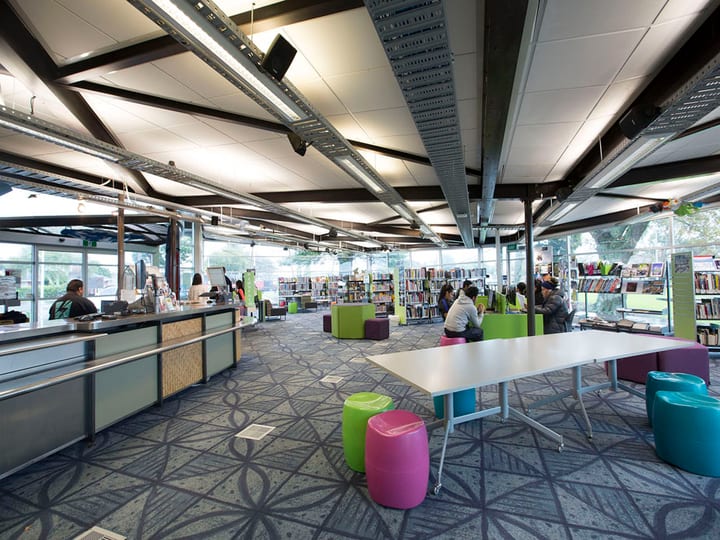 Open-plan library interior with colourful seating, bookshelves and patterned carpet