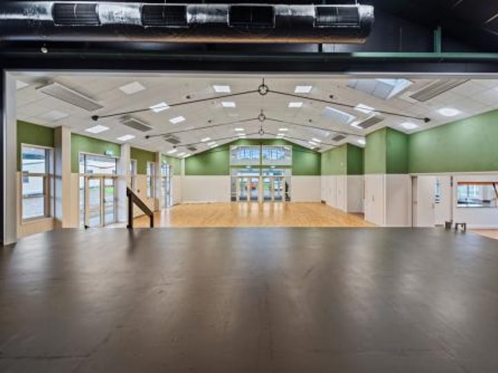 Hall interior viewed through roller door opening, green walls and timber floor