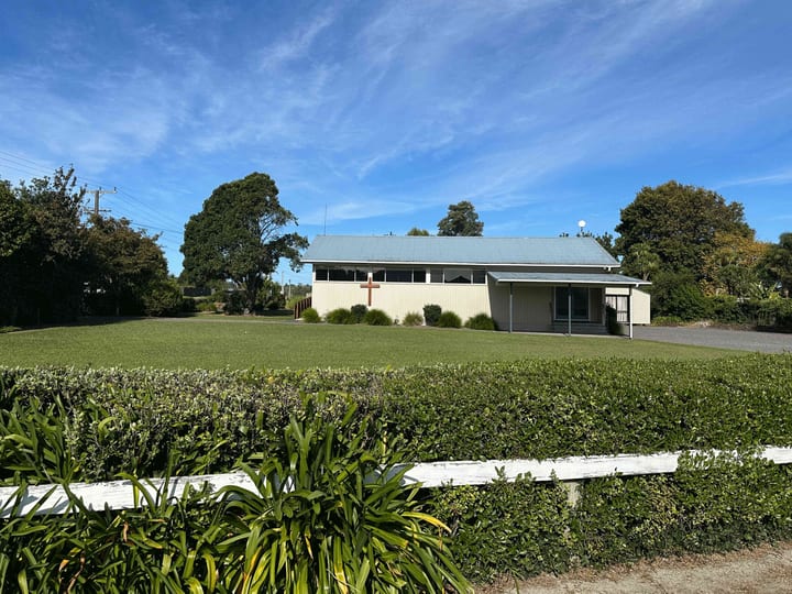 Dark grey church building with large signage reading Helensville Community Church and cross on roofline