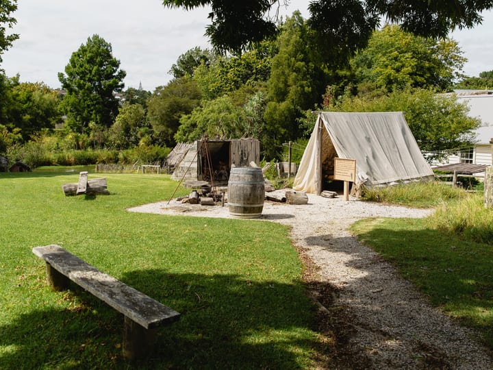 Historical village grounds with tent structure, barrel and period buildings
