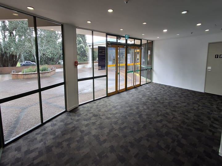 Interior lobby with dark carpet, large windows, and automatic glass entry doors