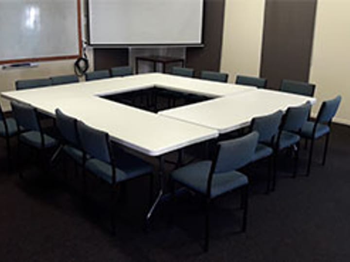 Smaller meeting room with U-shaped table and whiteboard