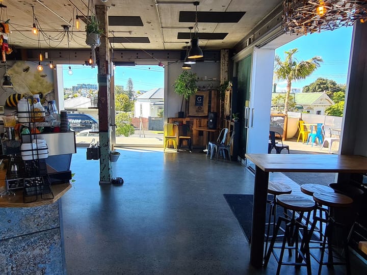 Cafe interior from entrance showing counter, open roller door, and outdoor area