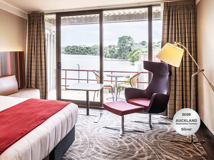 Hotel room with king bed, striped headboard and balcony overlooking water