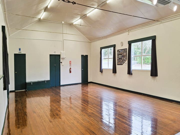 Hall interior with timber floor, vaulted white ceiling and windows with dark curtains