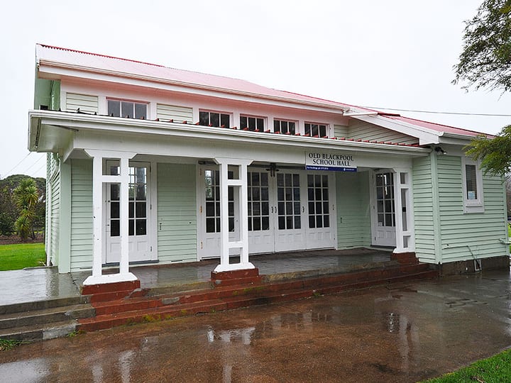 White timber hall with covered veranda, French doors, and red iron roof, wet forecourt