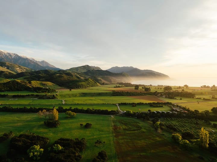 Aerial view of rural valley with farmland, mountains, and coastline