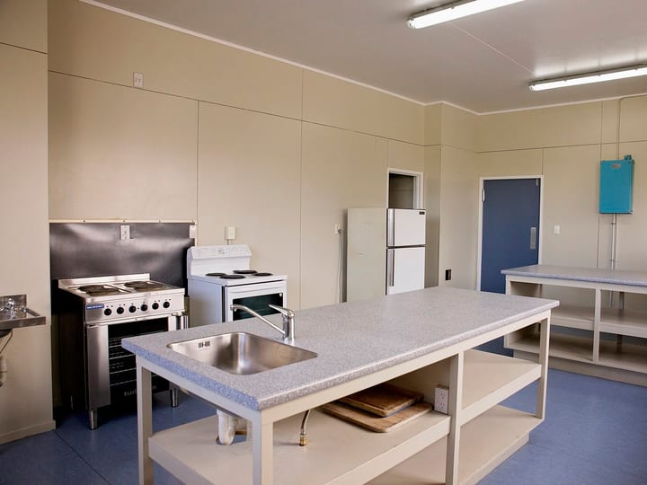 Spacious community kitchen with island bench, sink and appliances