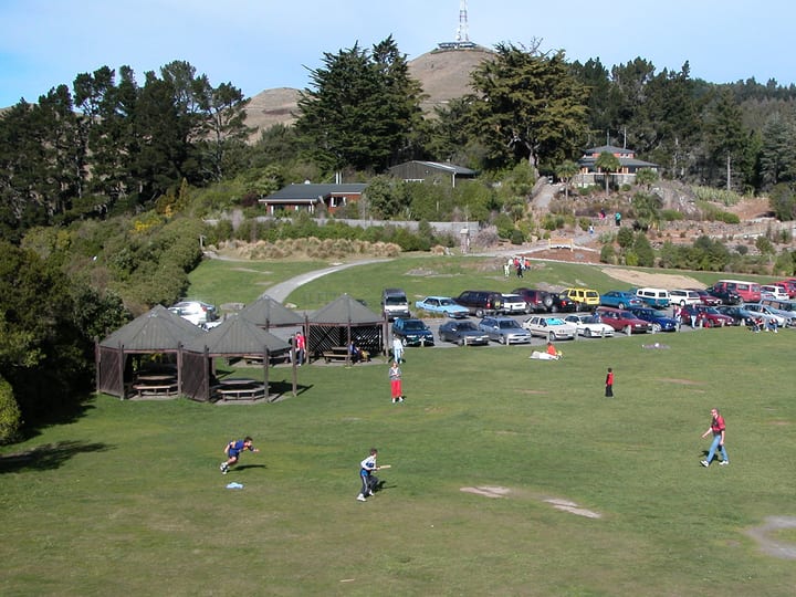 Open park area with lawn, pavilion shelters and hillside in background