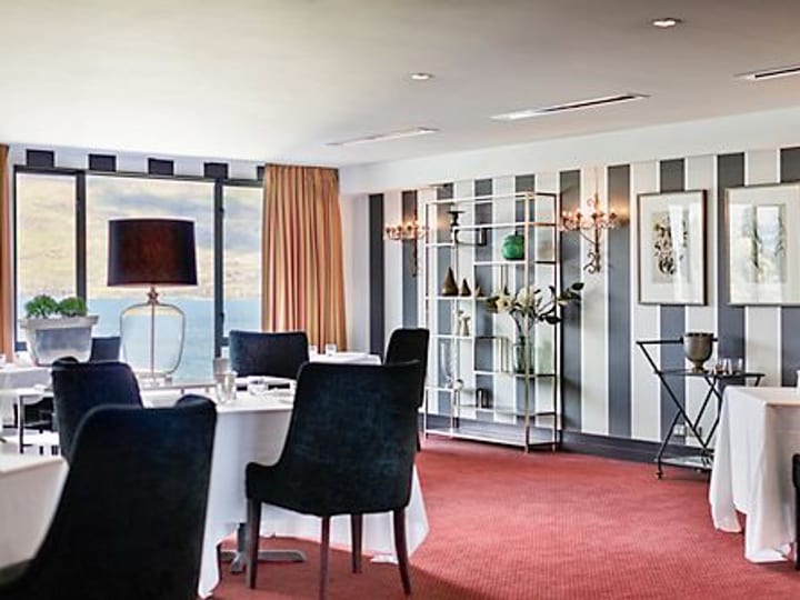 Restaurant dining room with striped feature wall, round tables and lake view through window