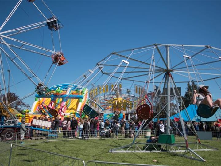 Fairground rides and crowds on open grass at outdoor show event