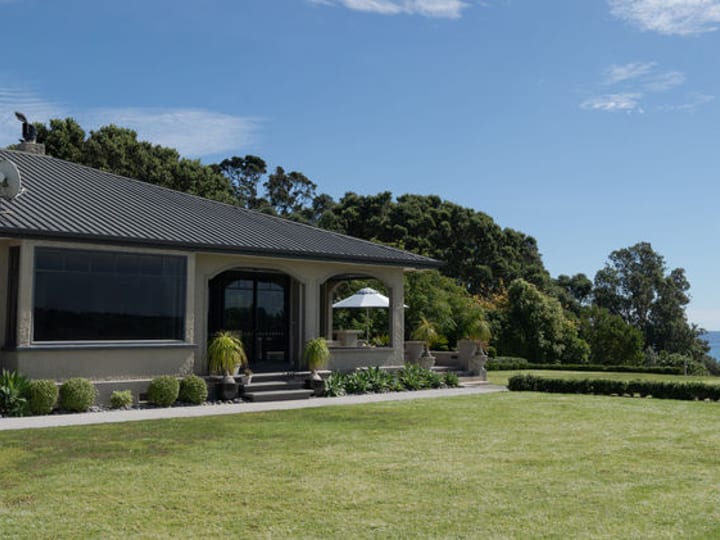 Low-rise venue building with arched entry and sea view from lawn