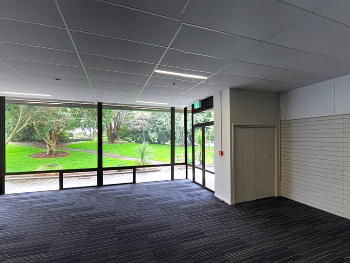Empty function room with tiled carpet, white walls and external glazing