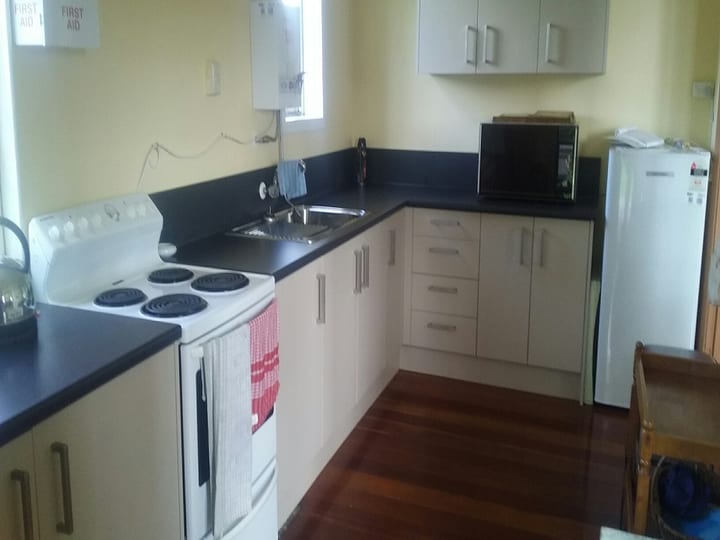 Basic kitchen with stove, sink, microwave and timber floor