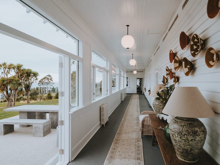White-painted hallway with pendant lights, woven wall hangings and view to outdoor seating