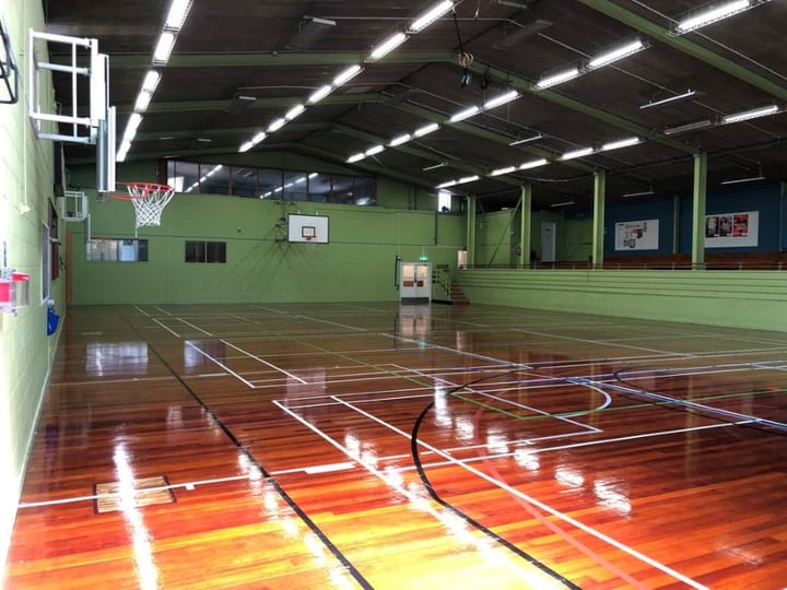 Large indoor sports hall with wooden floor and basketball hoops