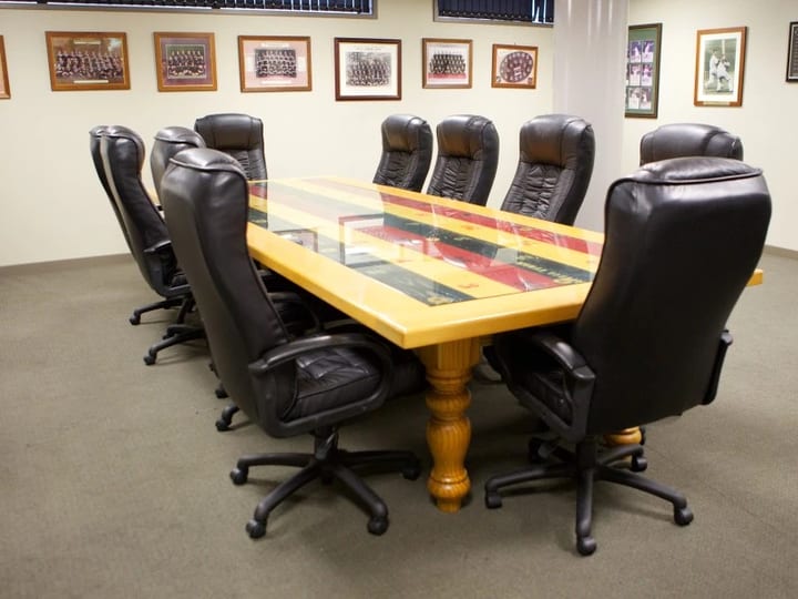 Boardroom with large timber table, leather chairs and sports memorabilia walls
