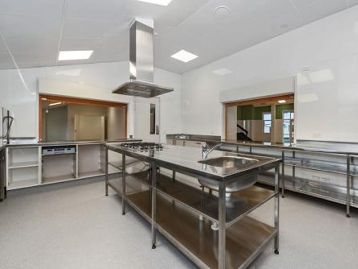 Commercial kitchen with stainless benches, sink and serving window