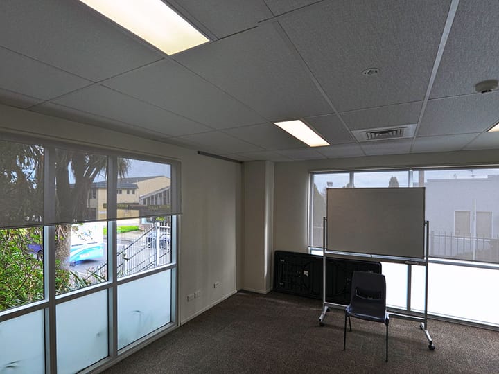Small empty meeting room with carpet tiles and windows overlooking rooftops