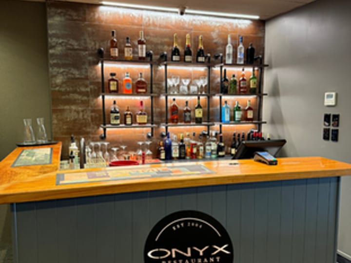 Bar counter with branded signage and shelved spirits display