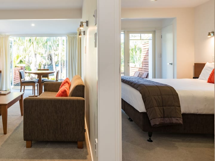 Suite with lounge area, TV, and adjoining bedroom visible through doorway