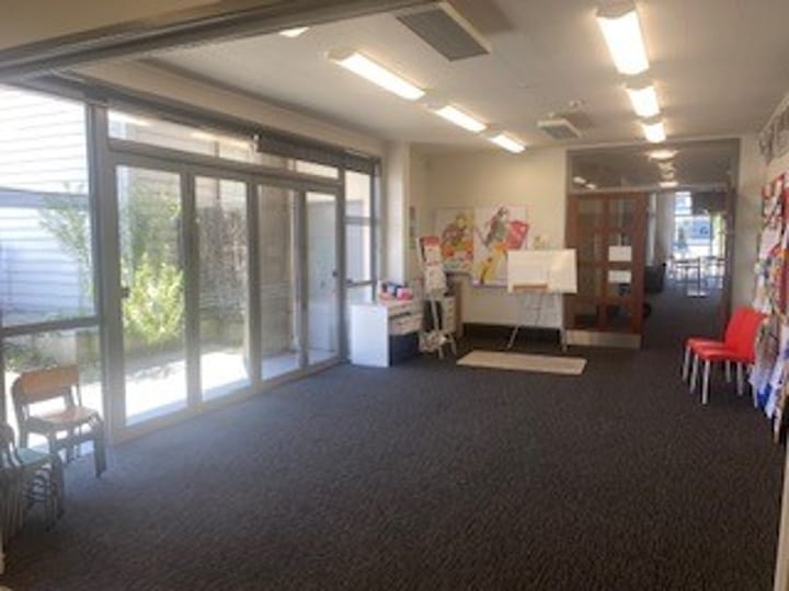 Small carpeted room with glass entry doors and scattered chairs