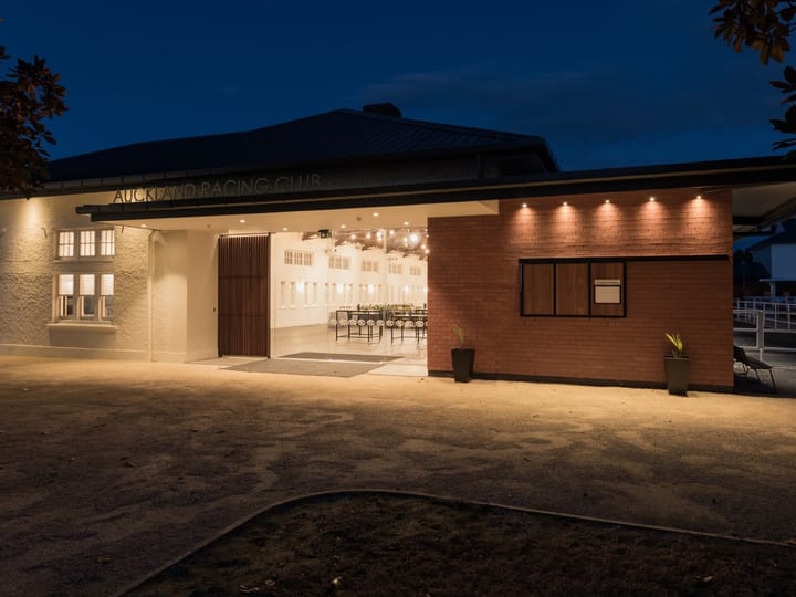 Low single-storey venue exterior lit at night with open doors revealing a set room