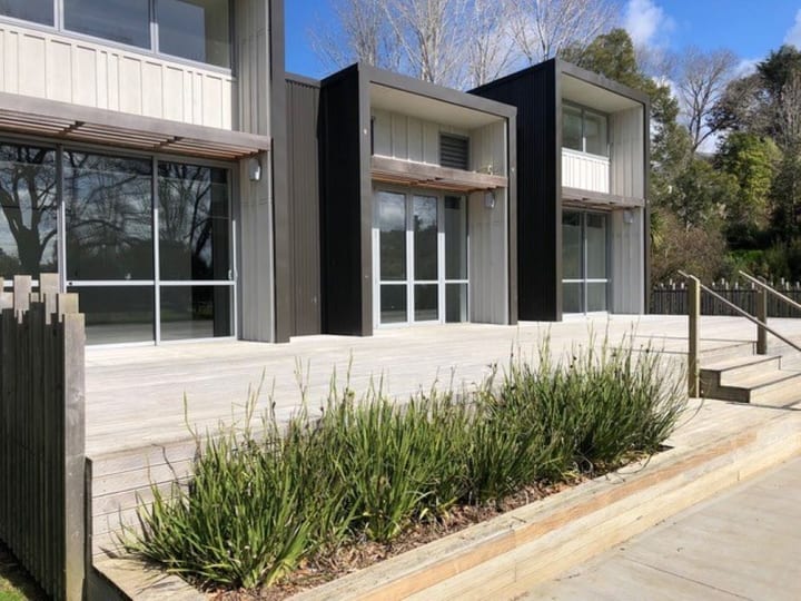 Dark cladding and glazed facade at close range with a wide timber deck and low planting below
