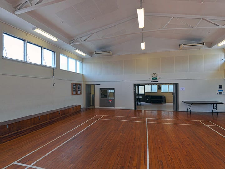 Large hall with timber sports floor, high ceiling and fluorescent lighting