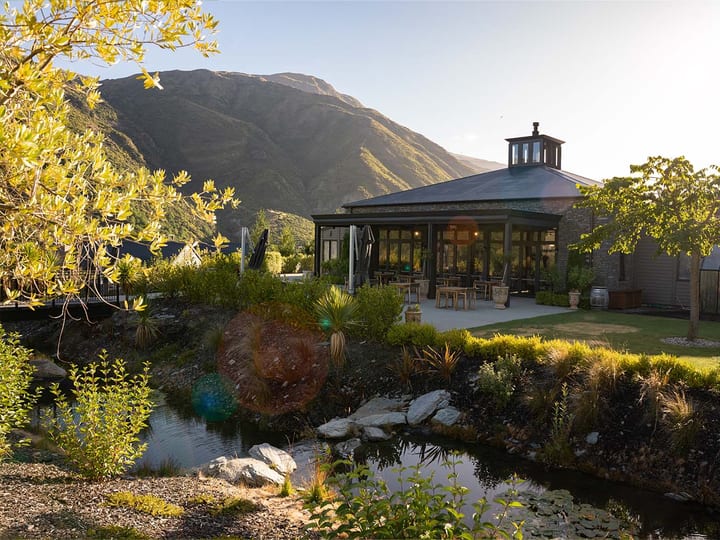 Pavilion building with pond, garden and mountain backdrop at sunset