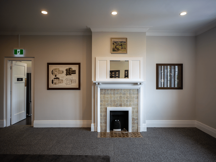 Room interior showing white fireplace surround with framed prints and mirror above