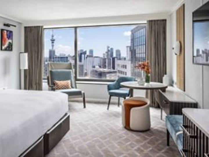Hotel bedroom with king bed and floor-to-ceiling city skyline view