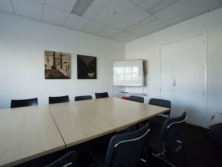Meeting room with large table, chairs, whiteboard and artworks on wall