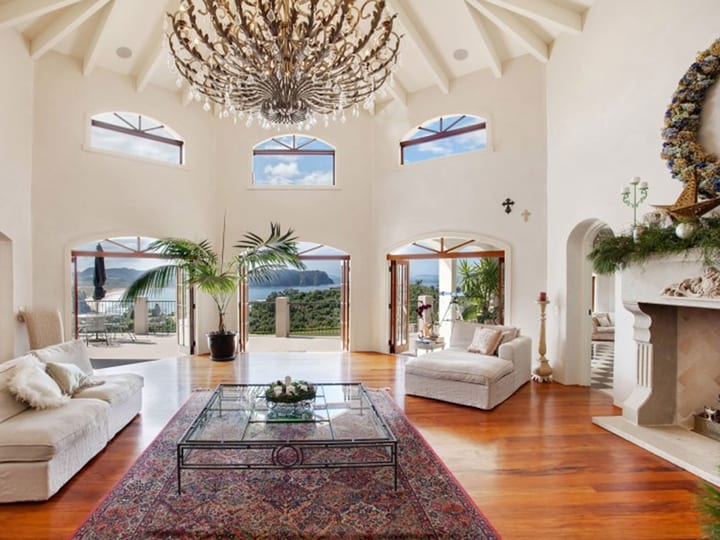 Grand living room with a vaulted ceiling, chandelier, arched French doors and timber floors