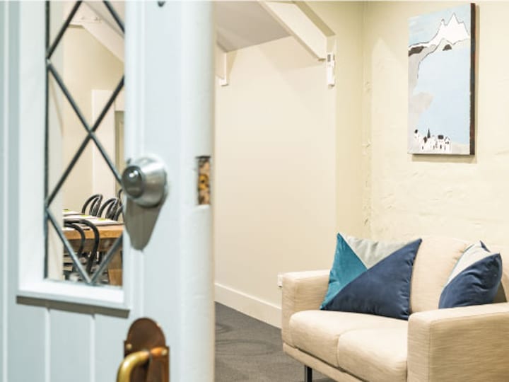 Hallway entrance with glazed Dutch door opening to cream lounge with coastal artwork