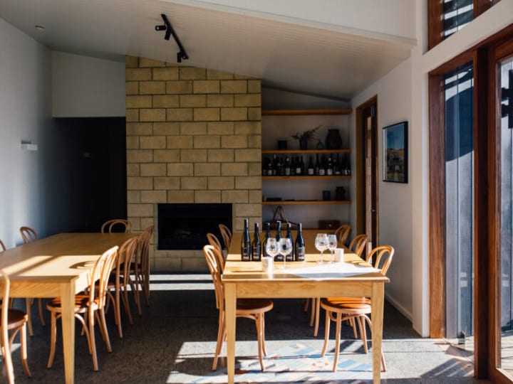 Timber-tabled meeting room with bentwood chairs, stone fireplace, and wine bottles on shelves