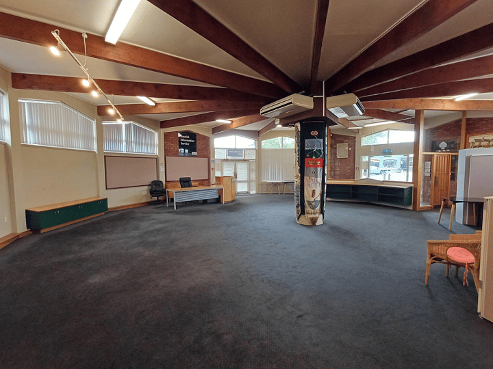 Large open room with timber beam ceiling, carpet, central decorative column and information displays