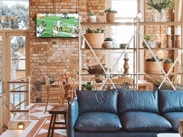 Pub interior with exposed brick, patterned floor tiles, blue sofa and shelving