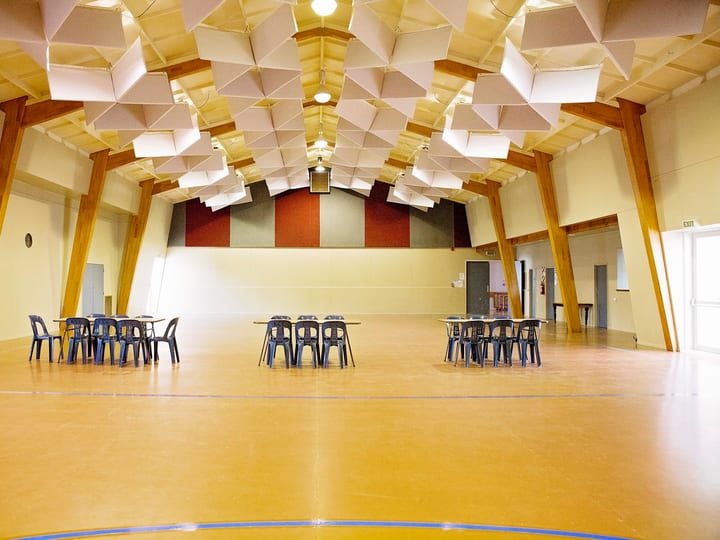 Large hall with timber-framed ceiling, tables and chairs set out