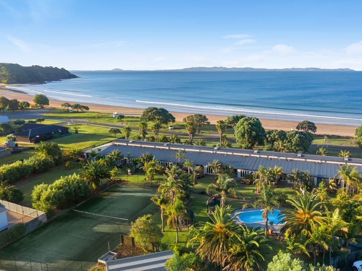 Aerial view of beachfront property with tennis court, pool, and grounds