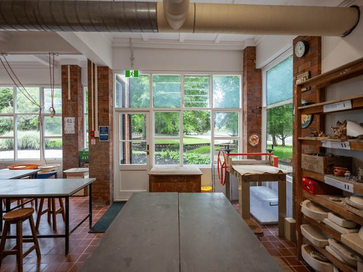 Craft studio with brick columns, work tables, pottery wheels and large windows to garden